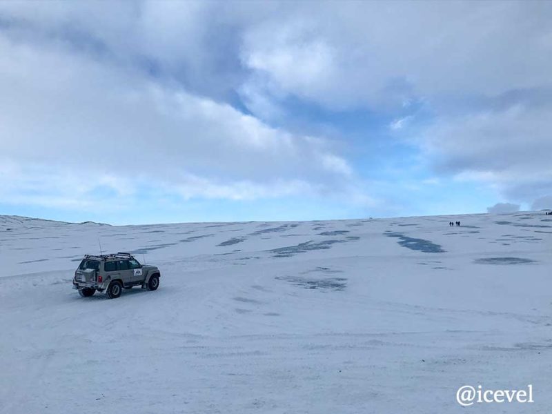スーパージープと氷河の上をハイキングしている人たち